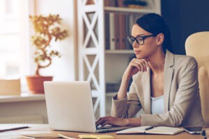 A woman with glasses uses her laptop to retrieve her NPN.