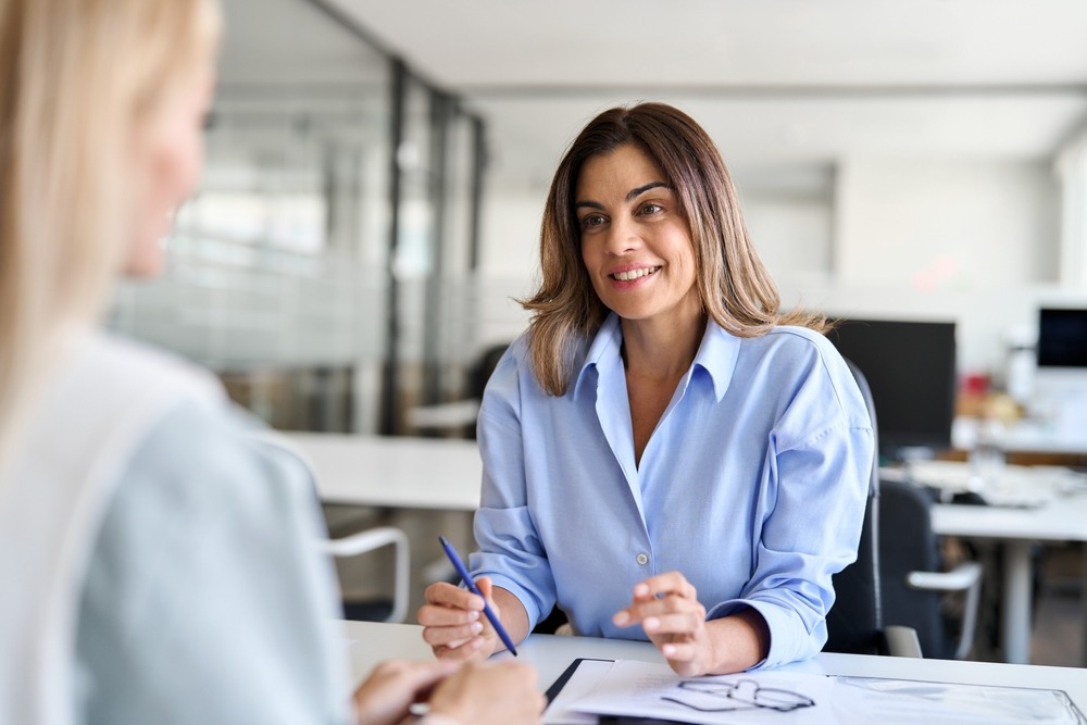 A professionally dressed woman sits at her lawyer’s desk and asks, “How long does a professional license defense case take?”