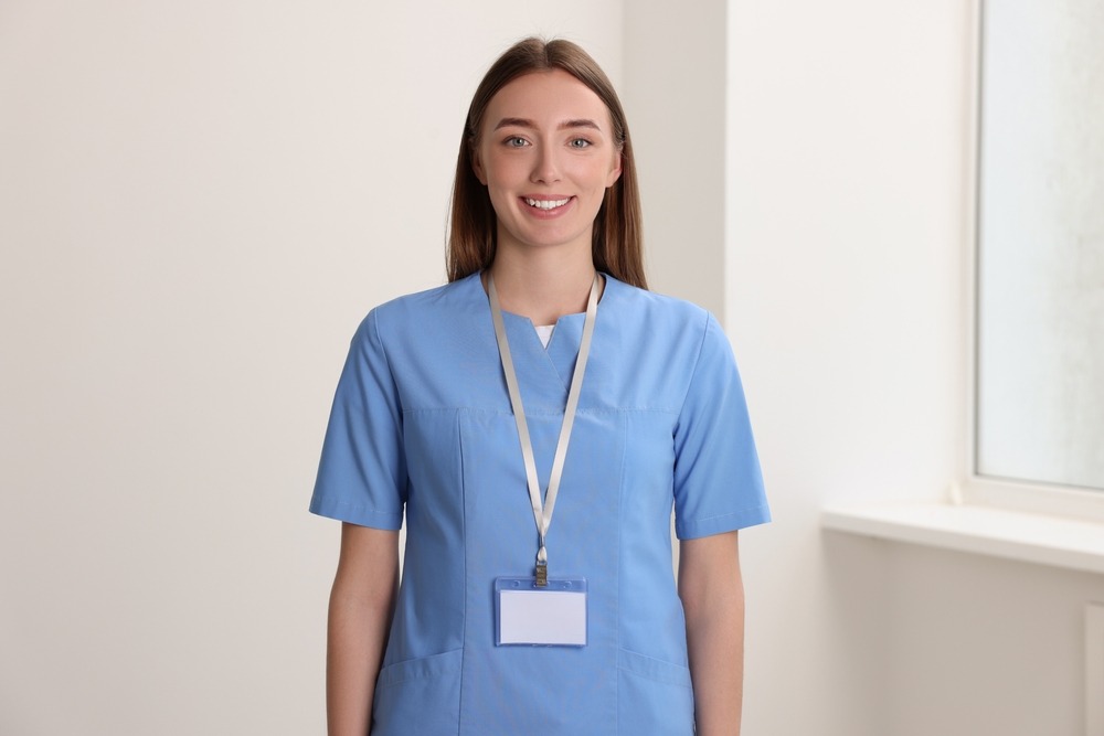 Smiling female nurse in scrubs with badge hanging around her neck